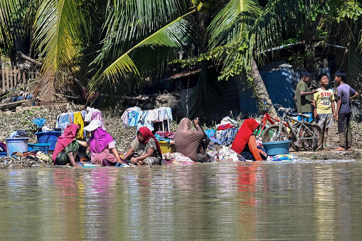People wash their belongings from the mud in the aftermath of flash floods in Meureudu, Pidie Jaya district in Indonesia's Aceh province on 30 November 2025. The death toll from floods that hit Indonesia this week has risen to more than 300 people, according to figures from the disaster agency on 29 November.