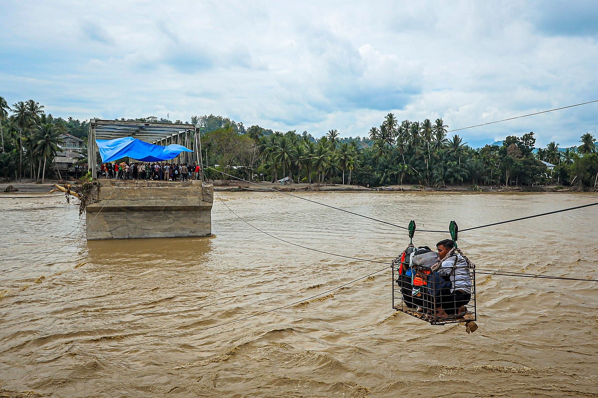 Villagers use a makeshift cable car to cross the river after the bridge was destroyed by a flash flood in Bireuen, Indonesia's Aceh province, on 2 December, 2025