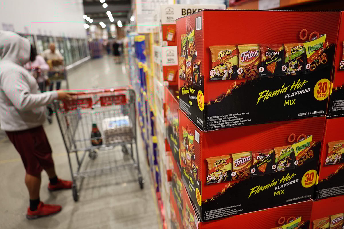 Boxes of PepsiCo's Frito-Lay Flamin' Hot flavored snacks including Cheetos, Fritos, Doritos tortilla chips, and Funyuns are displayed alongside packaged foods for sale at a warehouse grocery store in Hawthorne, California on 2 December 2025.