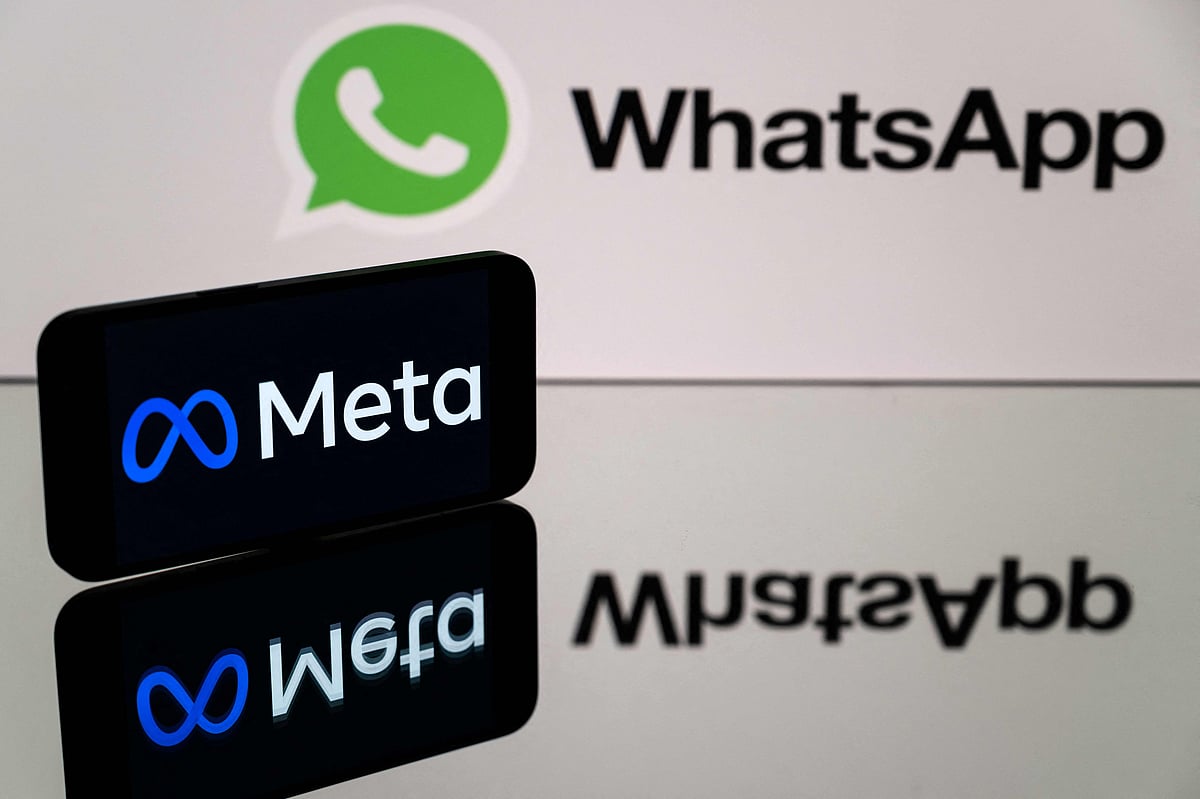 This photograph taken on 12 January 2023 in Toulouse, southwestern France shows a smartphone and a computer screen displaying the logos of WhatsApp app and its parent company Meta