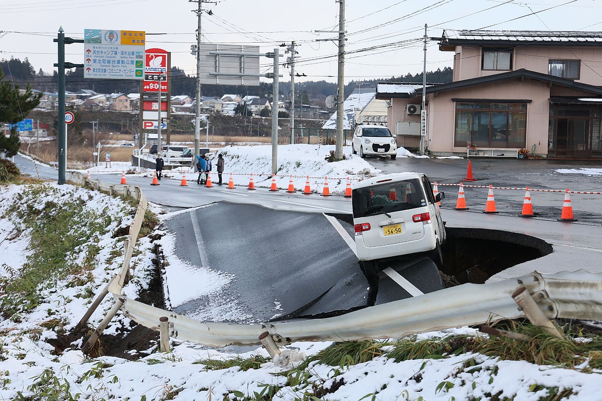 A vehicle rests on the edge of a collapsed road in Tohoku town in Aomori Prefecture on 9 December, 2025, following a 7.5 magnitude earthquake off northern Japan.