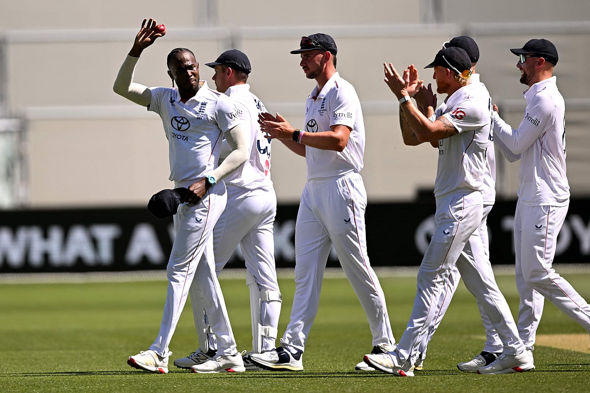England bowler Jofra Archer (L) holds the ball aloft after claiming his fifth wicket on the second day of the third Ashes cricket Test match between Australia and England at the Adelaide Oval in Adelaide on 18 December, 2025