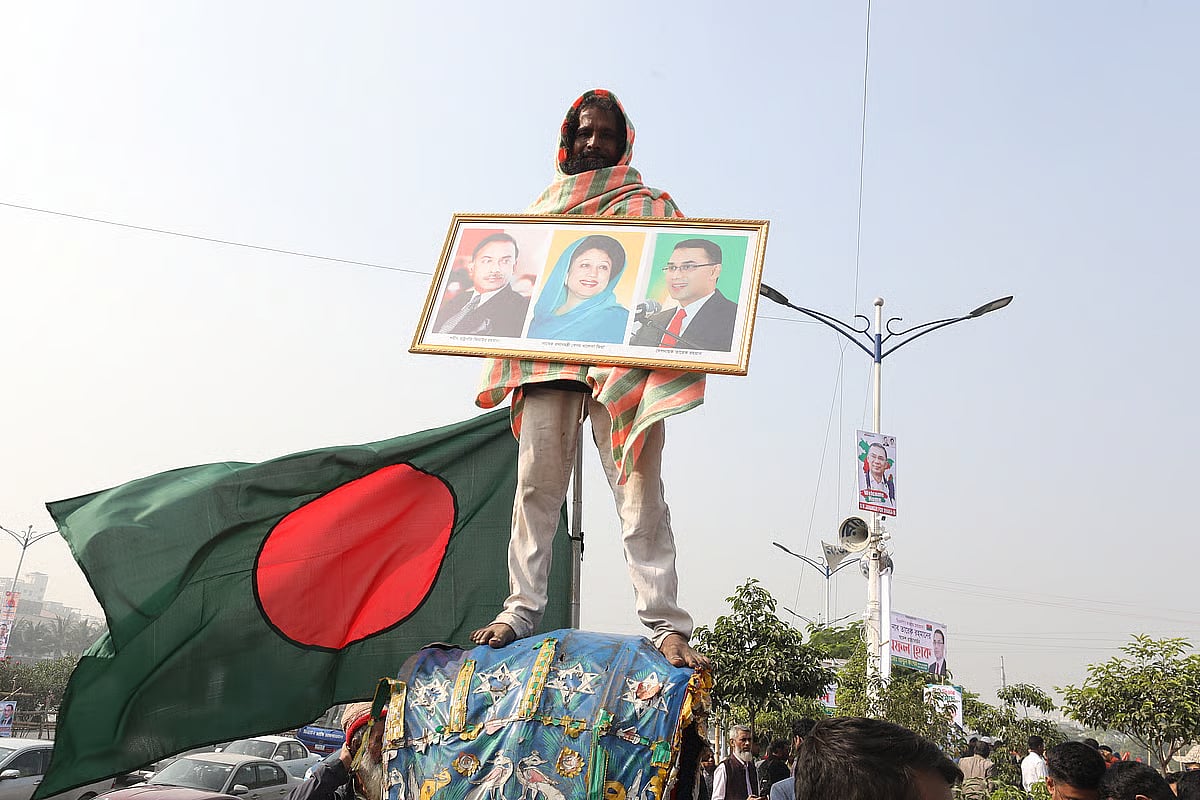 A party supporter holding portraits of Ziaur Rahman, Khaleda Zia, and Tarique Rahman