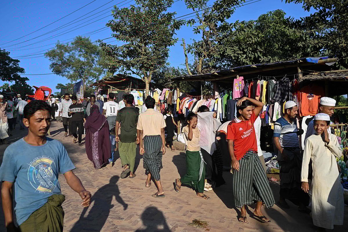 This photograph taken on 18 December 2025 shows Rohingya refugees walking along a market at the Kutupalong refugee camp in Bangladesh's Ukhia.