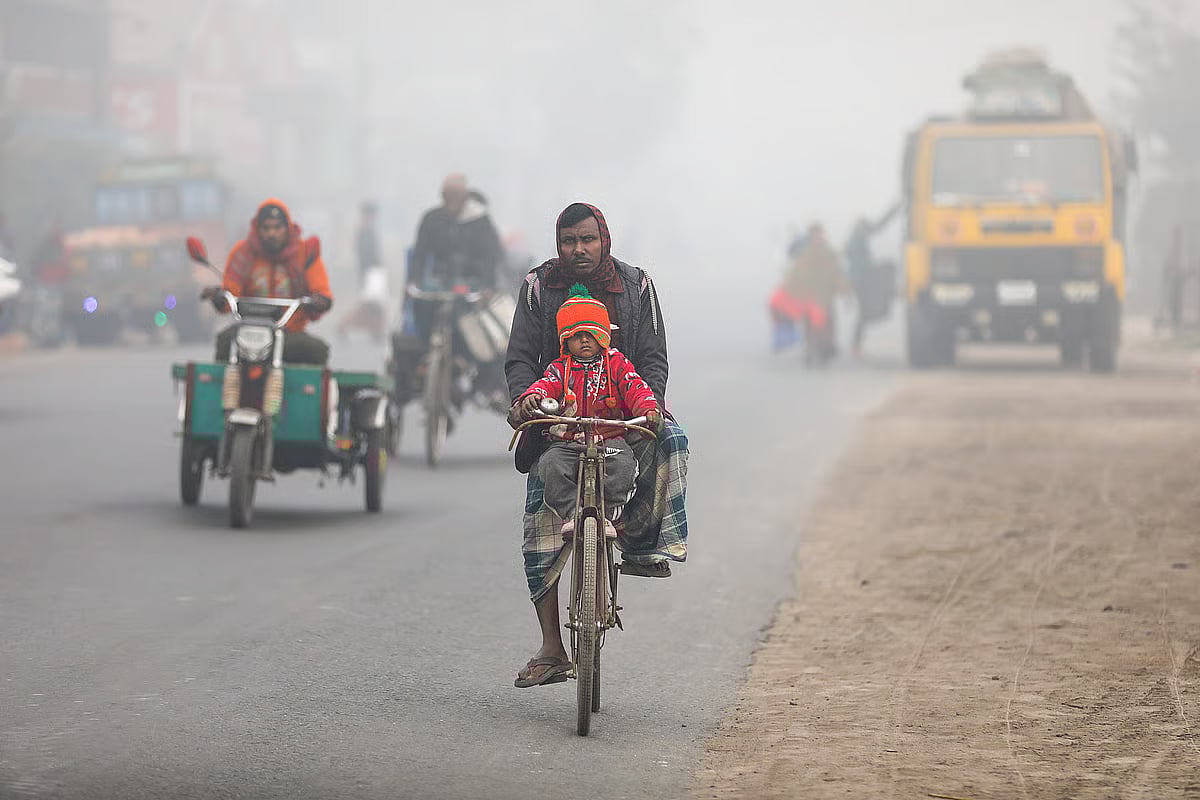 A child rides on a bicycle with his father in the biting cold. Photo taken in Nawapara area of Jashore on 26 December 2025.