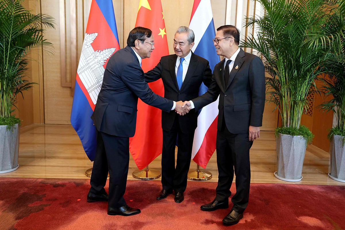 This handout photo taken and released by Agence Kampuchea Press (AKP) on 29 December 2025 shows China's Foreign Minister Wang Yi (C) looking as Cambodia's Deputy Prime Minister Prak Sokhonn (L), who is also the country's Foreign Minister, shakes hands with Thailand's Foreign Minister Sihasak Phuangketkeow (R) during a meeting in China's Yunnan province