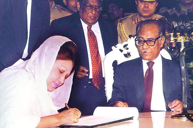 Khaleda Zia signs in the oath book after being sworn on as prime minister in 1991. President at the time, Justice Shahabuddin Ahmed is by her side