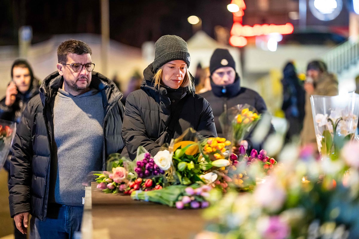 Mourners gather in front of flowers and candles laid near the site where a fire ripped through a crowded bar during New Year's Eve celebrations in the Alpine ski resort town of Crans-Montana on 1 January, 2026.