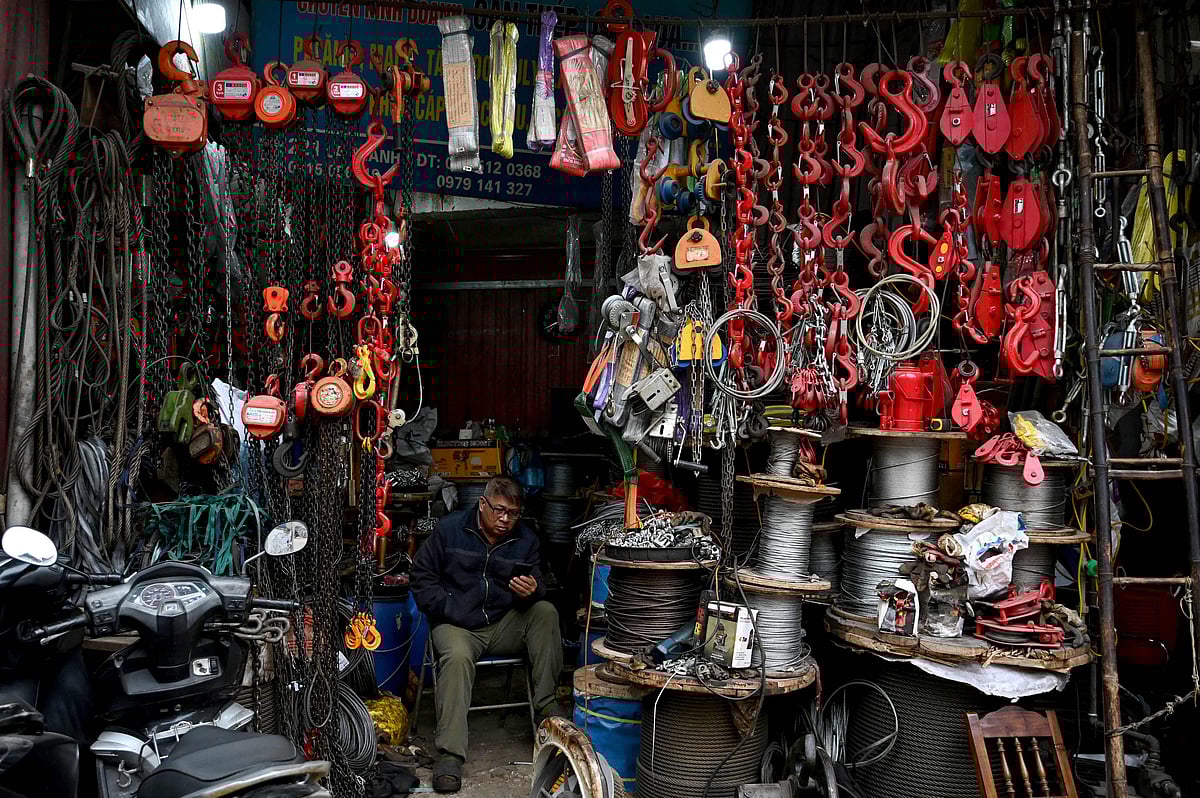 A man uses his mobile phone as he waits for customers in a household goods store in Hanoi on January 5, 2026. Vietnam said on January 5 its economy grew 8.0 percent last year, thanks to gains in services, construction and exports and despite fresh US tariffs taking effect.