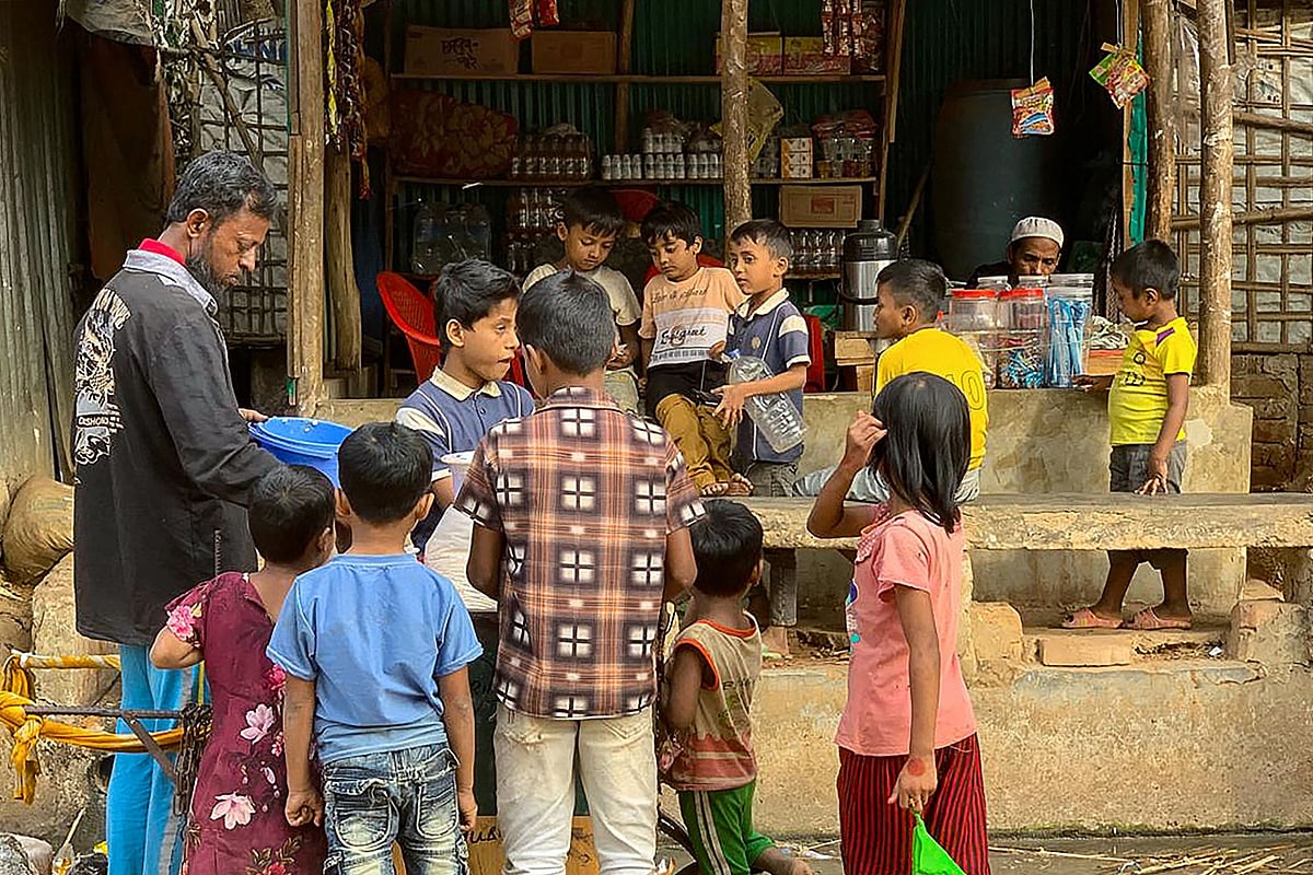 Rohingya refugee children surround a street vendor at the Kutupalong refugee camp in Ukhia on January 11, 2026.
