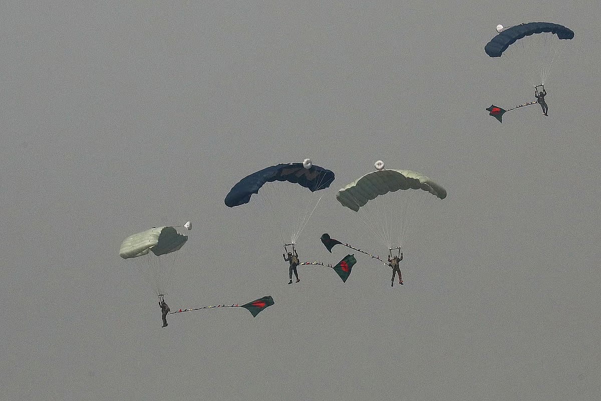Participants in a special parachute jump carry the national flag in Dhaka on 16 December 2025.