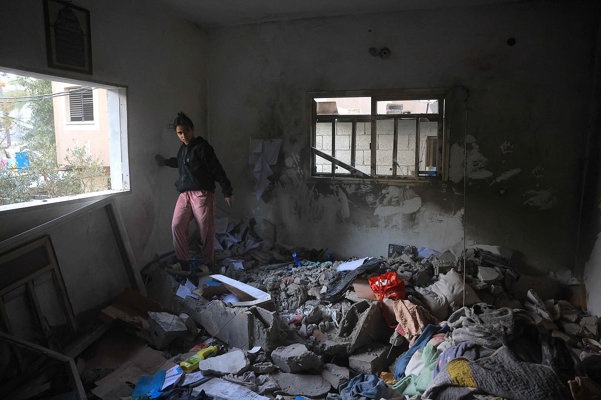 A Palestinian woman walks on the debris in a room, after an Israeli military attack on the home of the al-Houli family, in which four people were reportedly killed, west of Deir al-Balah, in the central Gaza Strip on 16 January 2026.