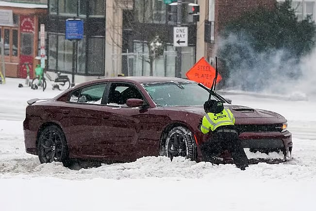 A car stuck in snow is being pushed out of a driveway in Washington, USA. 25 January, 2026