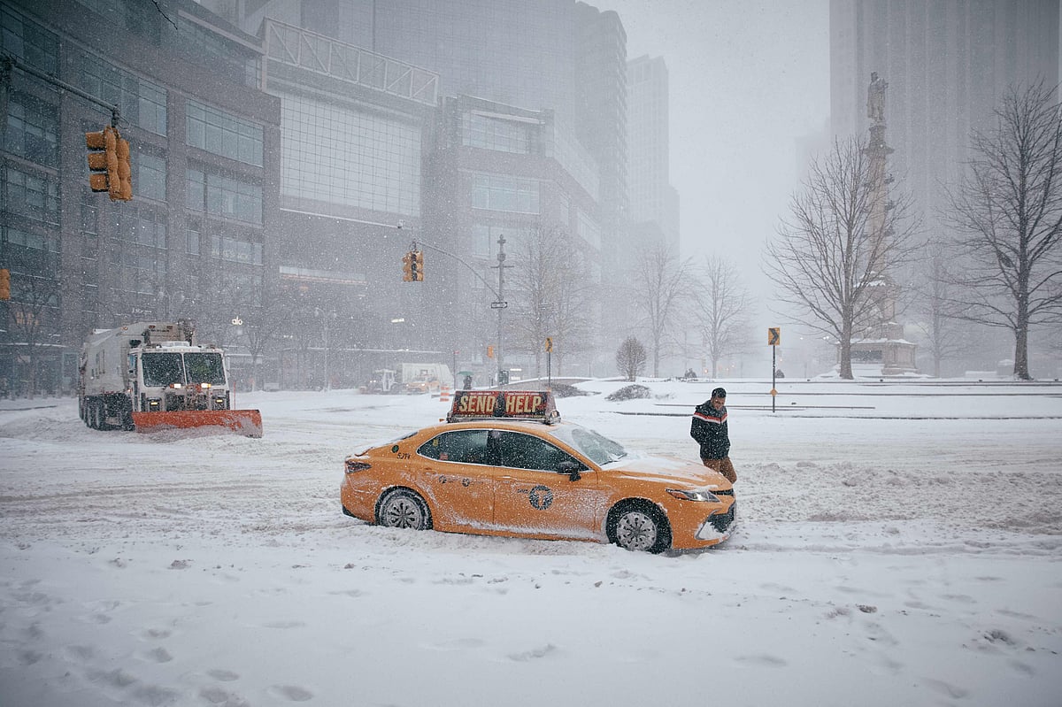A taxi driver gets out of his car after it becomes stuck in the snow at Columbus Circle during a snowstorm on January 25, 2026 in New York City