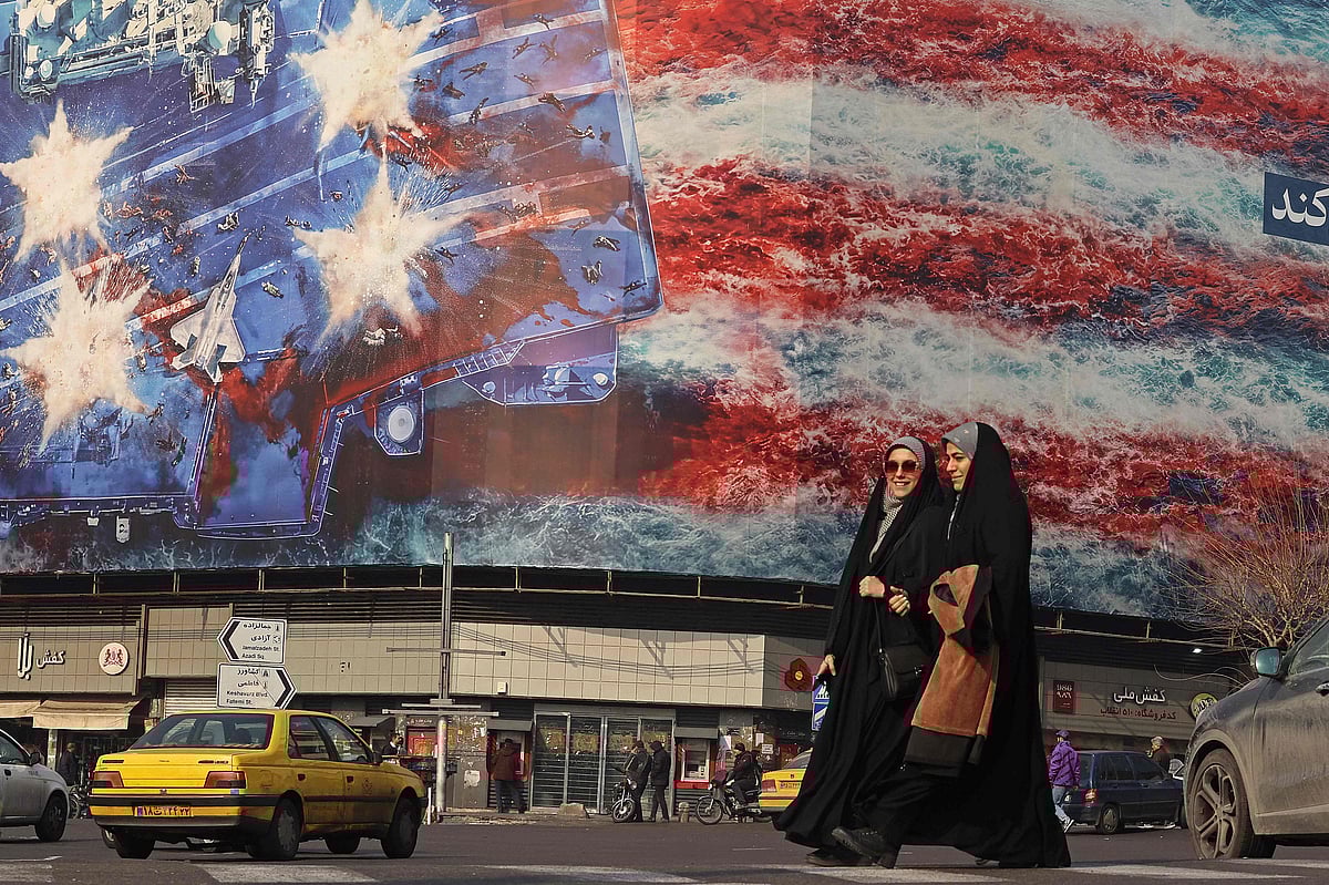 Iranian women walk past an anti-US billboard installed on a building at the Enqelab Square in Tehran on 26 January, 2026.