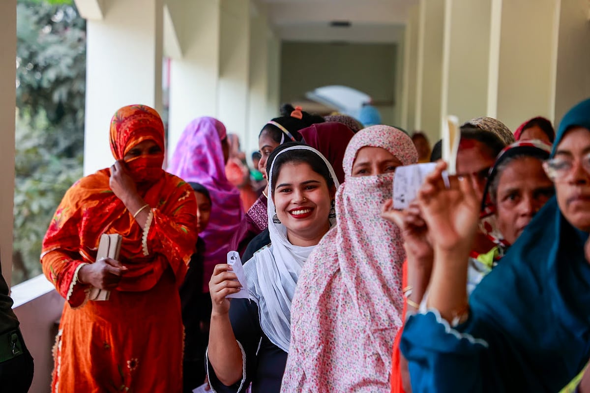 Women shows voter slips standing  in queue to cast ballots in the 13th parlimentaray election on 12 February 2026.