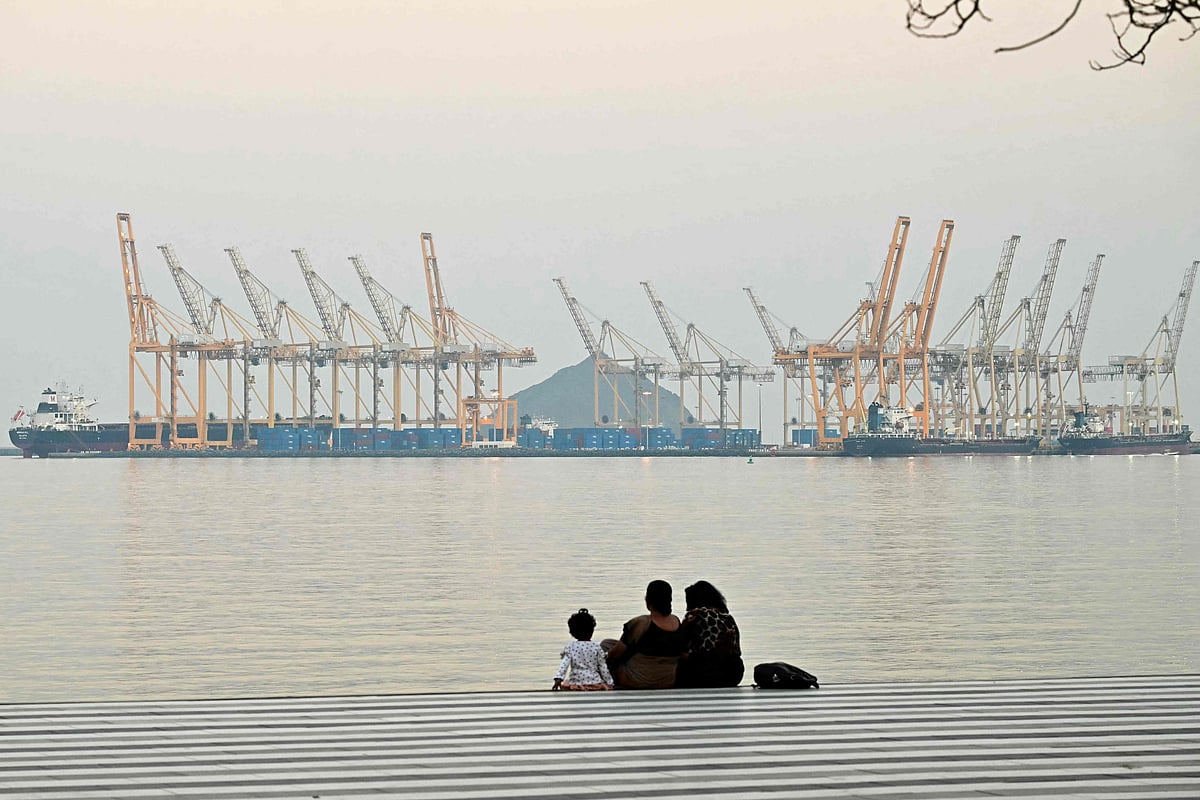 A family sits against the backdrop of a dockyard off coast city of Fujairah, in the Strait of Hormuz in the northern Emirate on February 25, 2026.