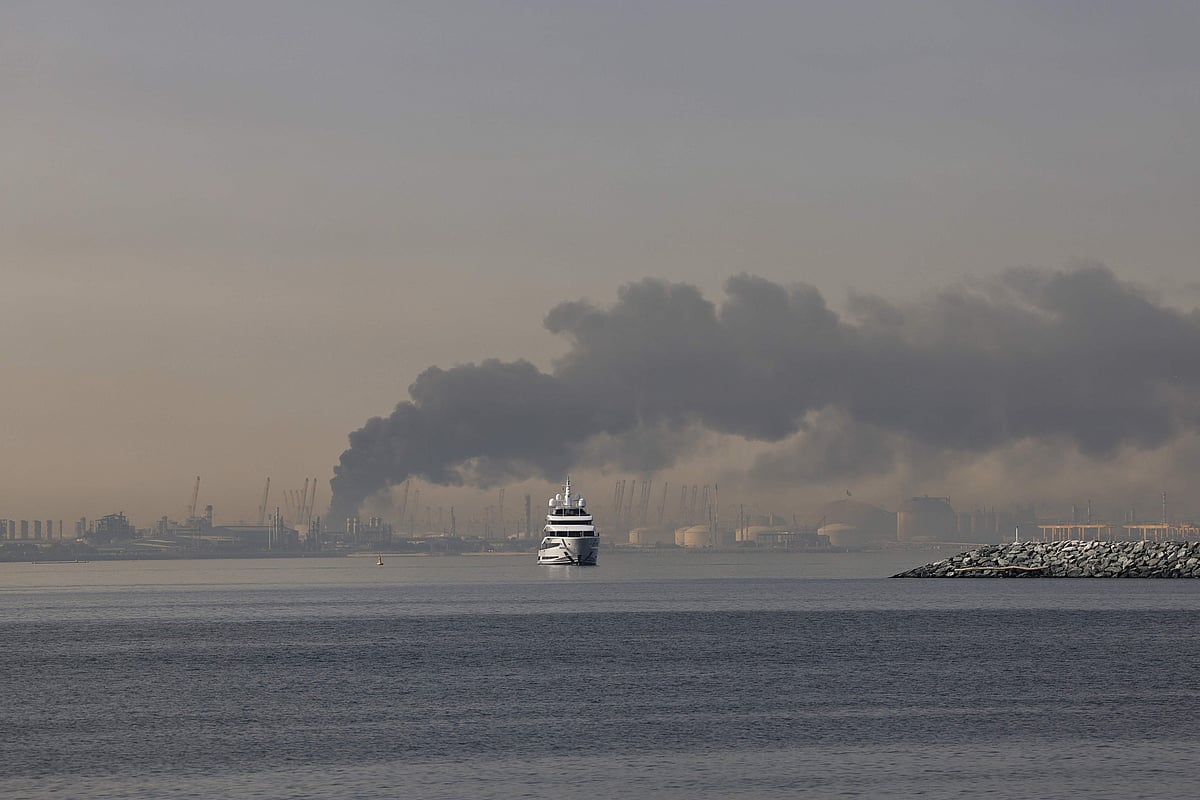 A yacht sails past a plume of smoke rising from the port of Jebel Ali following a reported Iranian strike in Dubai on March 1, 2026.