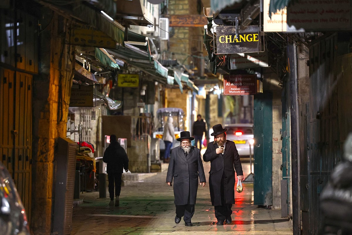 Jewish ultra-Orthodox men walk past shuttered store fronts in the empty Old City of Jerusalem on March 12, 2026. One week after the start of the Israeli-US offensive against Iran, days and nights of millions of Israelis are interrupted by repeated sirens warning them to head to shelters from incoming Iranian missiles.