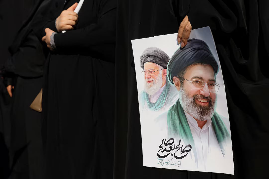 A woman holds an image of Iran's new supreme leader, Mojtaba Khamenei, alongside late Iranian Supreme Leader Ayatollah Ali Khamenei, during a funeral ceremony for the Iranian military commanders who were killed in strikes, amid the US-Israeli conflict with Iran, in Tehran, Iran, 11 March, 2026. 