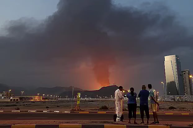 Foreign workers watch plumes of black smoke rising after an explosion in the industrial area of Fujairah, United Arab Emirates, on 3 March, 2026.