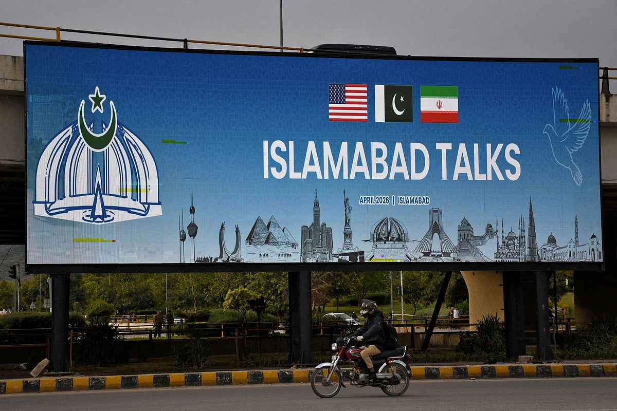 A man rides his motorbike past a billboard installed alongside a road as Pakistan prepares to host the U.S. and Iran for peace talks, in Islamabad, Pakistan, 10 April 2026.