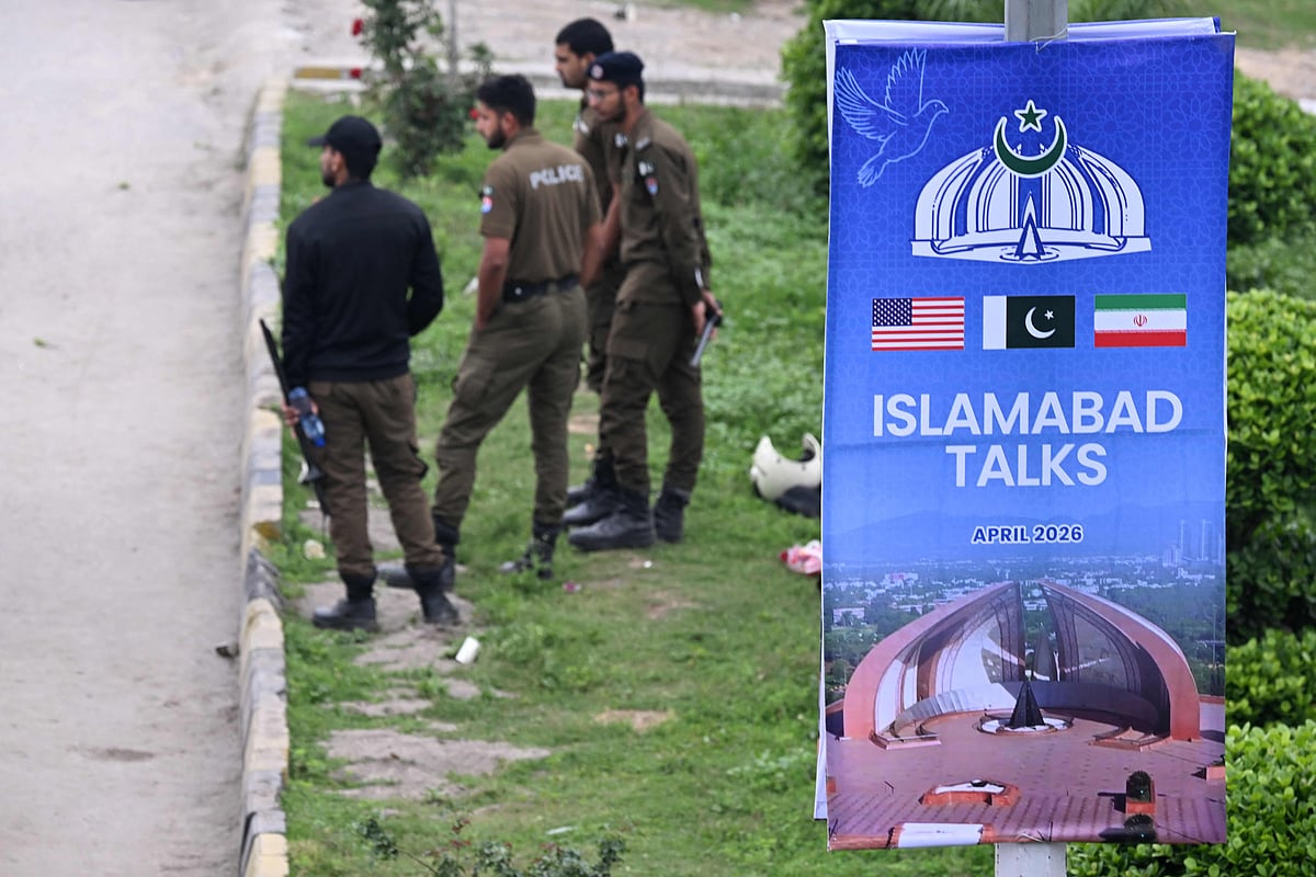 Policemen stand beside a poster on a street referencing the US-Iran peace talks in Islamabad on 11 April, 2026.