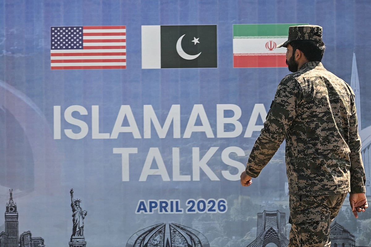 A Pakistani Ranger walks past a billboard for the US-Iran peace talks in Islamabad on 12 April 2026
