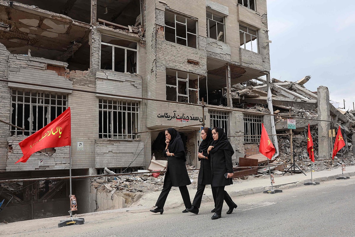 Iranian women walk past a residential building destroyed in a US-Israeli airstrike, in Tehran on 13 April 2026.