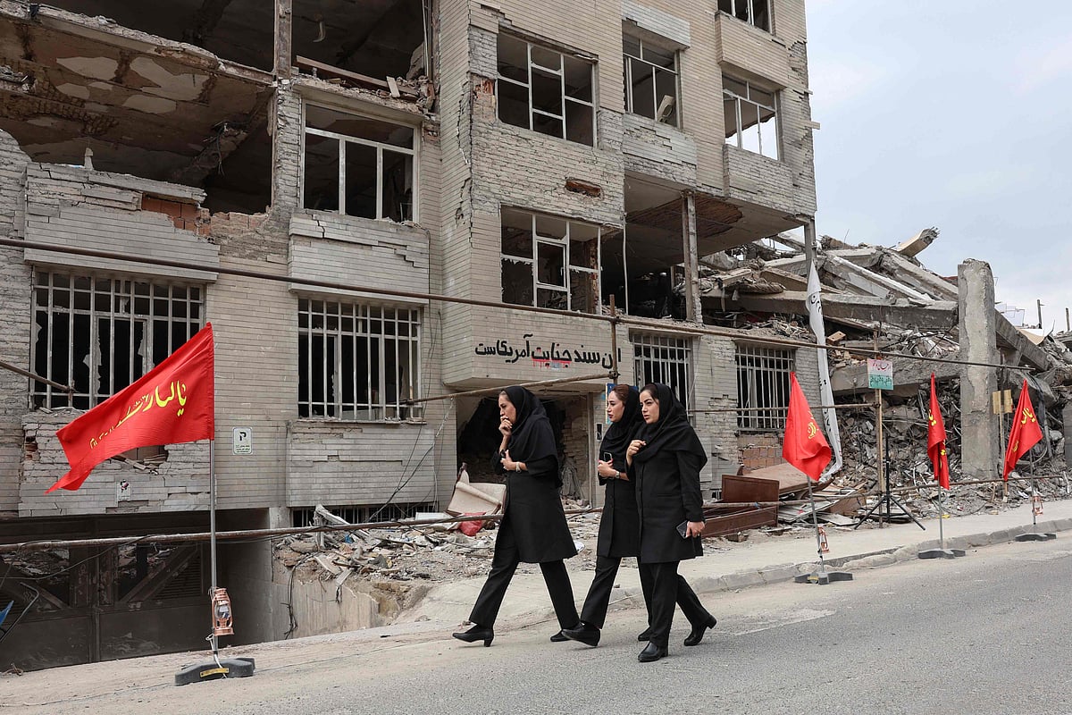 Iranian women walk past a residential building destroyed in a US-Israeli airstrike, in Tehran on April 13, 2026.