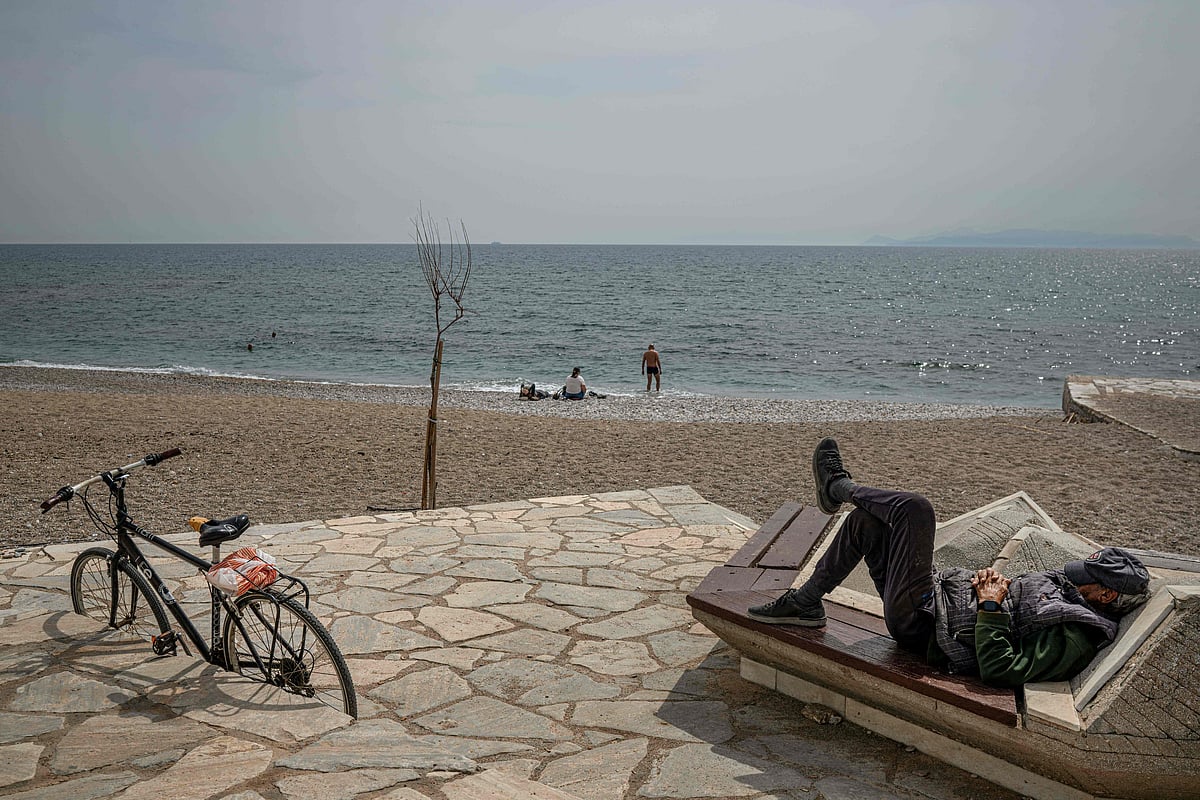 A man rests on a bench next to the sea at Alimos Beach near Athens on 15 April 2026.