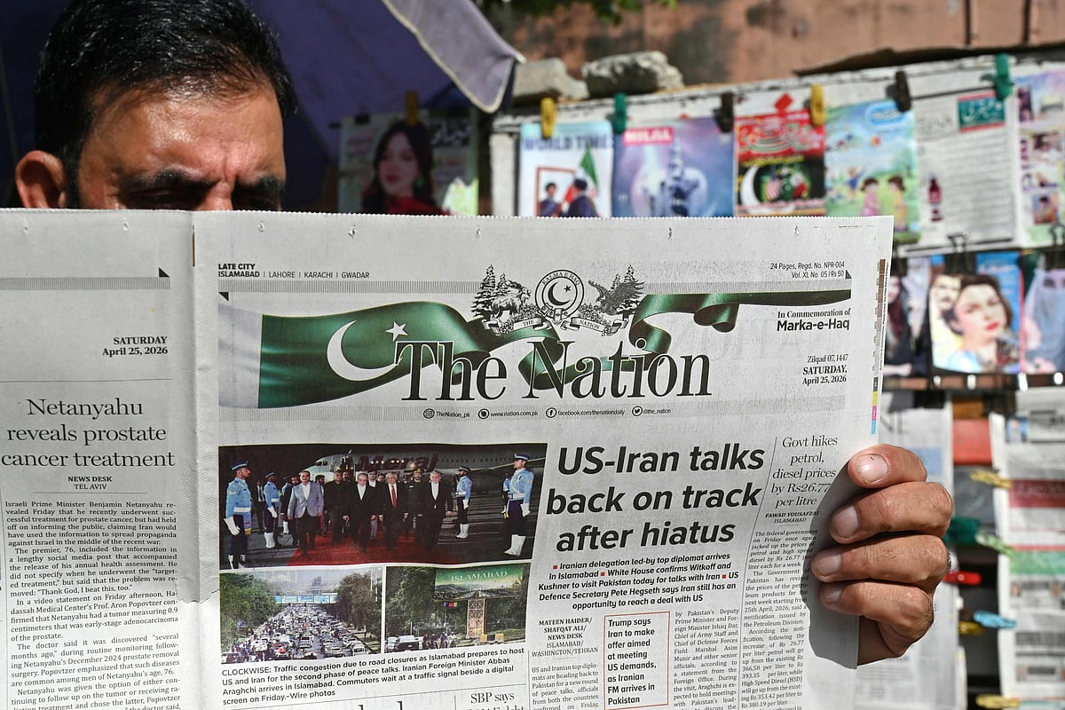A man reads a newspaper at a roadside stall in Islamabad on April 25, 2026. US envoys headed to the Pakistani capital on April 25 in a bid to kickstart a new round of peace negotiations with Iran amid a fragile ceasefire, though the prospect of direct talks remained uncertain. (Photo by Asif HASSAN / AFP)