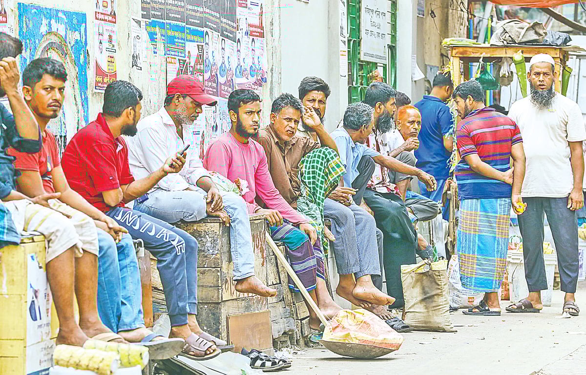 A group of day labourers wait to be hired, gathered in the early morning at a labour haat near the Fakirapool water tank area. The men represent different trades, masons, painters, and other manual workers, standing by the roadside in the hope of securing a day’s work.