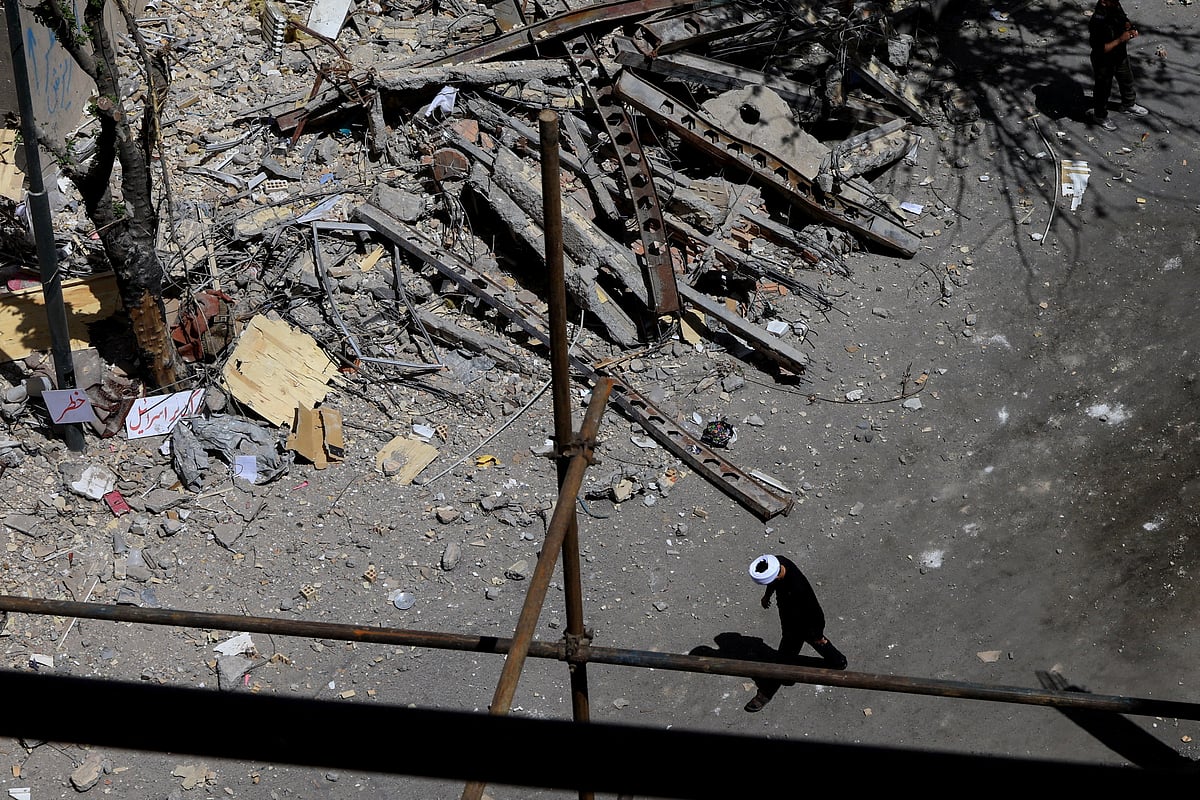 A cleric walks near a residential building damaged by a strike on March 4, in Tehran, Iran, 14 April 2026.
