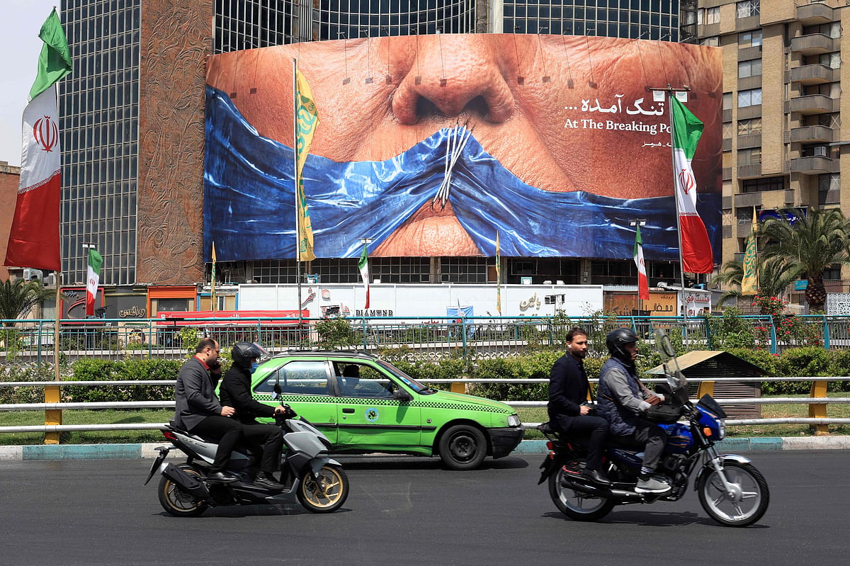 Motorists make their way past an anti-US billboard referring to President Donald Trump and the Strait of Hormuz, installed on a building at the Valiasr Square in Tehran on May 2, 2026. A senior Iranian military officer said on May 2 that renewed fighting between the US and Iran was "likely", hours after President Donald Trump said he was "not satisfied" with a new Iranian negotiating proposal. (Photo by AFP) /