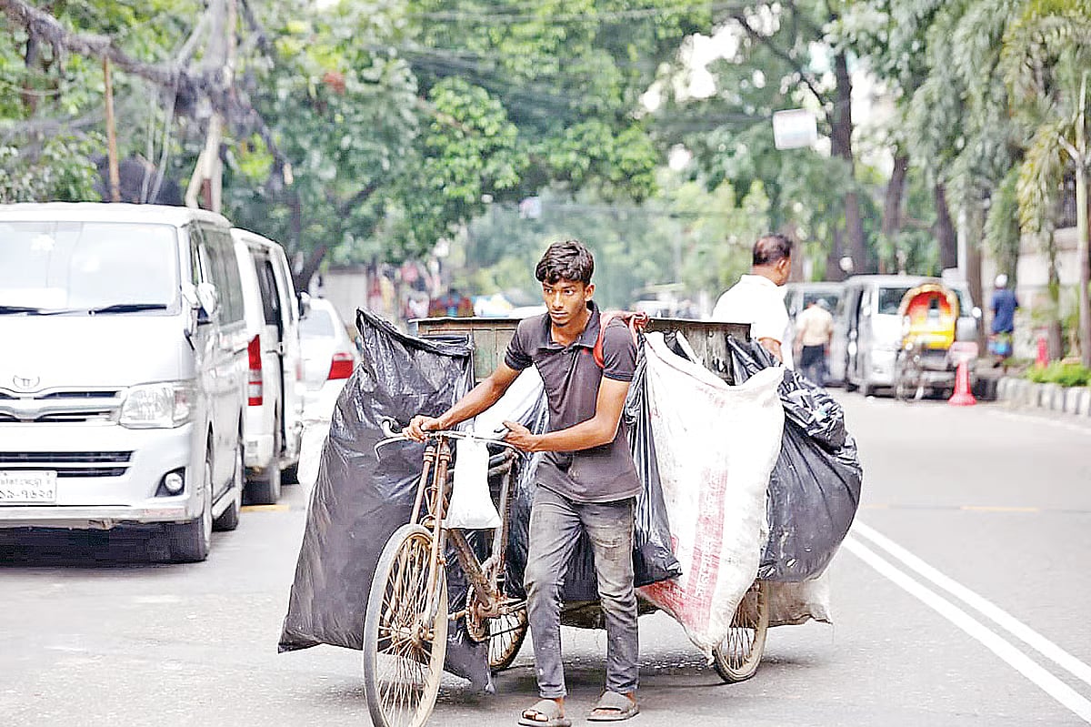 A worker of a van-based waste collection service collects household rubbish on Road No. 50 in the Gulshan 2 area, Dhaka in the afternoon on 12 May 2026