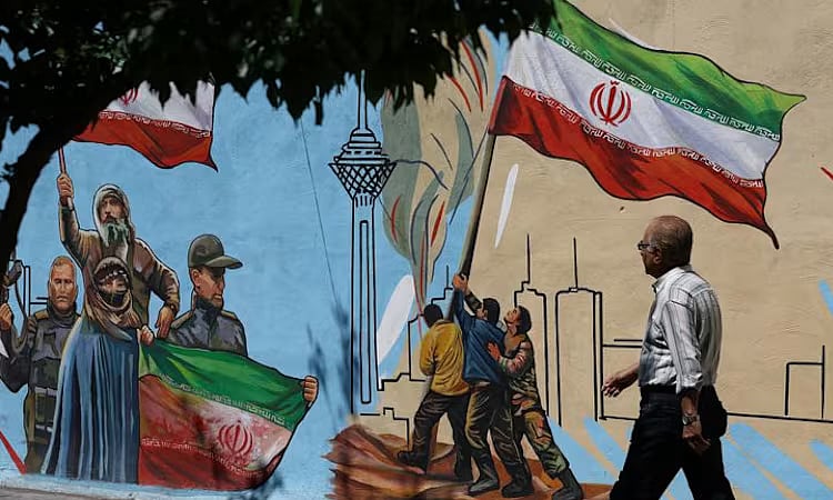 An Iranian man walks past an anti-USA and anti-Israel mural, in Tehran on 21 April, 2026.