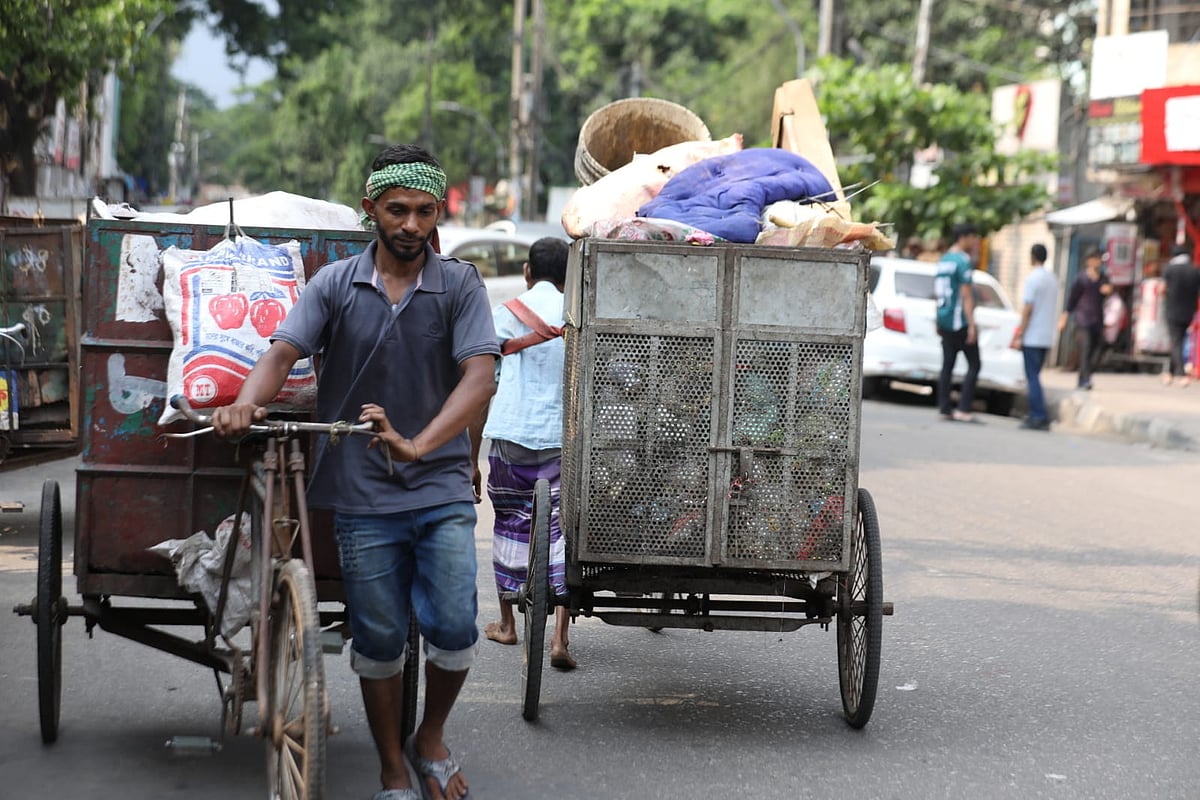 A worker of a van-based waste collection service collects household rubbish in the Palashi area, Dhaka on 13 May 2026