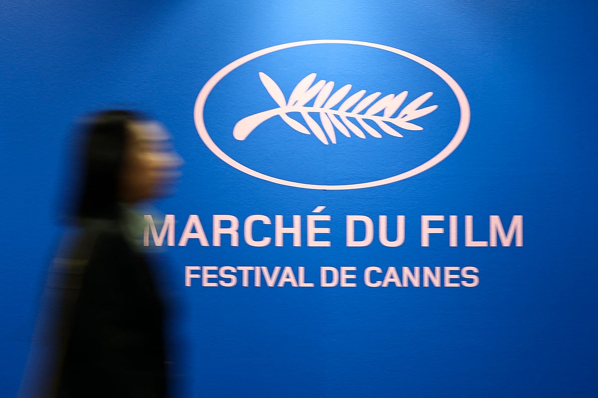 A woman walks past a poster of the Film Market with a Palm d'Or symbol, inside the Film Market business building before the start of the 79th Cannes Film Festival in Cannes, France, 12 May, 2026.