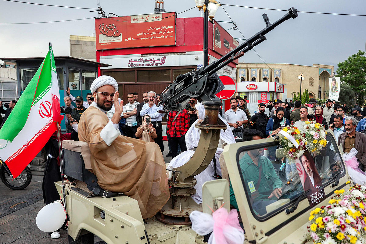 A Shia Muslim cleric waves while riding as a groom with his bride in a military jeep as they arrive for a public mass wedding ceremony at Imam Hossein Square in Tehran on 18 May 2026.