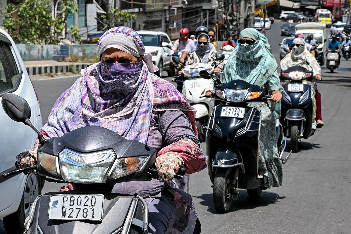 Commuters with their faces covered with cloth ride along a street on a hot summer afternoon in Amritsar on May 23, 2026. (Photo by Narinder NANU / AFP)