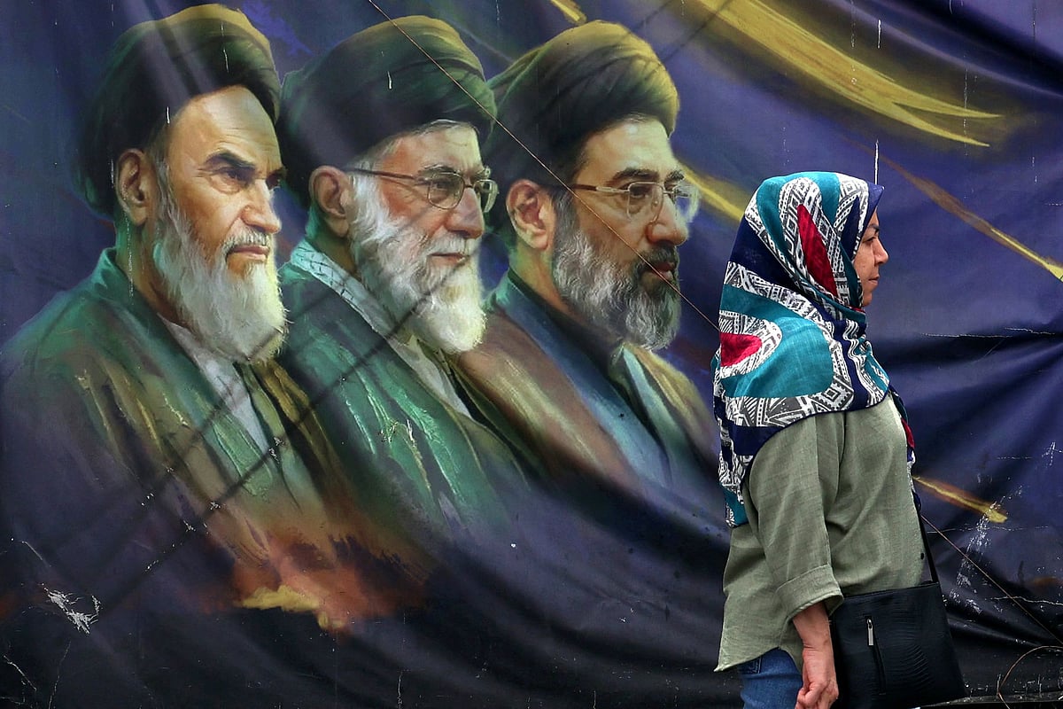 An Iranian woman walks past a billboard bearing the images of the late founder of the Islamic Revolution supreme leader Ayatollah Ruhollah Khomeini (L), the late Iranian supreme leader Ali Khamenei assassinated in February 2026, and his son, the current supreme leader Mojtaba Khamenei (R), erected along a street in Tehran on May 28, 2026. Iran's foreign ministry condemned on May 28, what it called violations by the United States after its strikes on the southern port city of Bandar Abbas and expressed solidarity with Oman after the US president threatened to "blow them up". (Photo by AFP) /