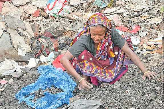 Anowara Begum collects charcoal from the remains of her fire-ravaged home, to sell for an income. The photo was taken at Kalshi slum in Mirpur on Saturday.