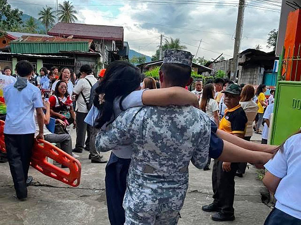 This handout photo taken and released on 8 June, 2026 by the Philippine Coast Guard shows a Coast Guard serviceman carrying an earthquake-affected student in Sta Cruz, Davao del Sur. A 7.8-magnitude earthquake that struck the southern Philippines on 8 June.