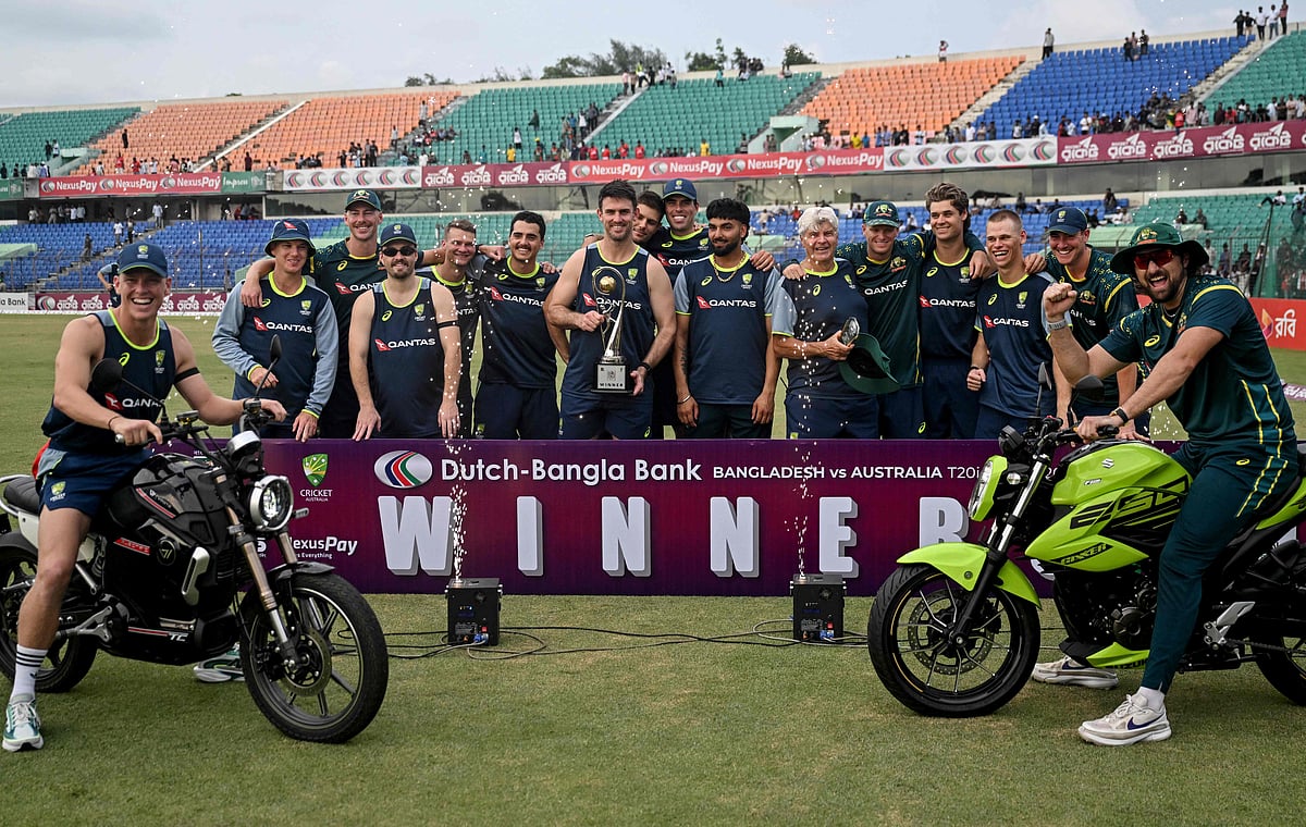 Australia's captain Mitchell Marsh (C) holds the series trophy alongside teammates during the presentation ceremony as they celebrate their team's win at the end of the third Twenty20 (T20) international cricket match between Bangladesh and Australia in the Bir Sreshtho Flight Lieutenant Matiur Rahman Stadium of Chattogram on J21 June 2026.