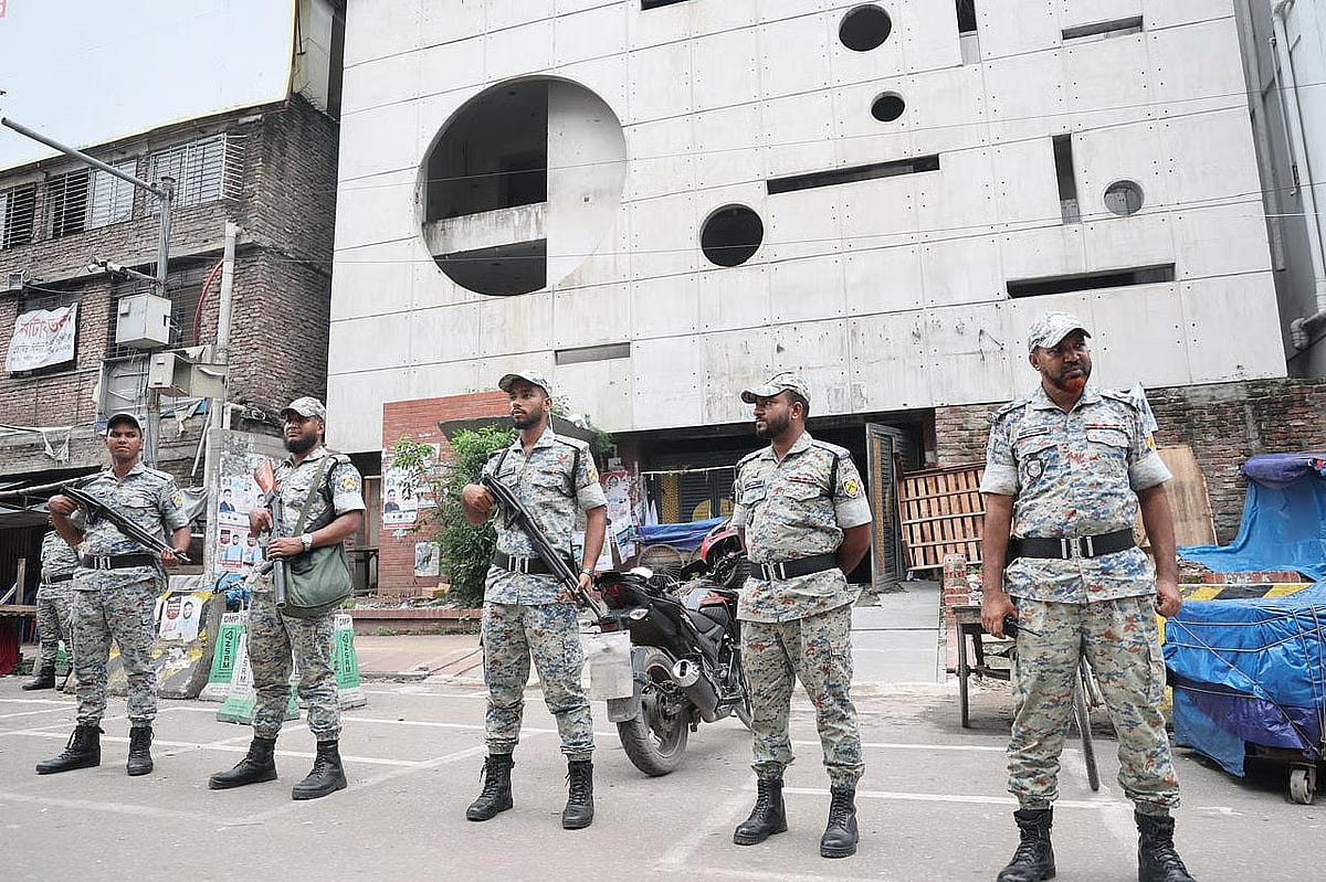 Law enforcement personnel stand guard in front of the head office of the Bangladesh Awami League, whose activities have been banned 