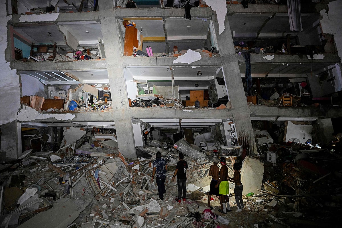 People stand in the rubble near a damaged building following an earthquake in Catia La Mar, La Guaira State, some 30kms north-west of Caracas, early on 25 June 2026