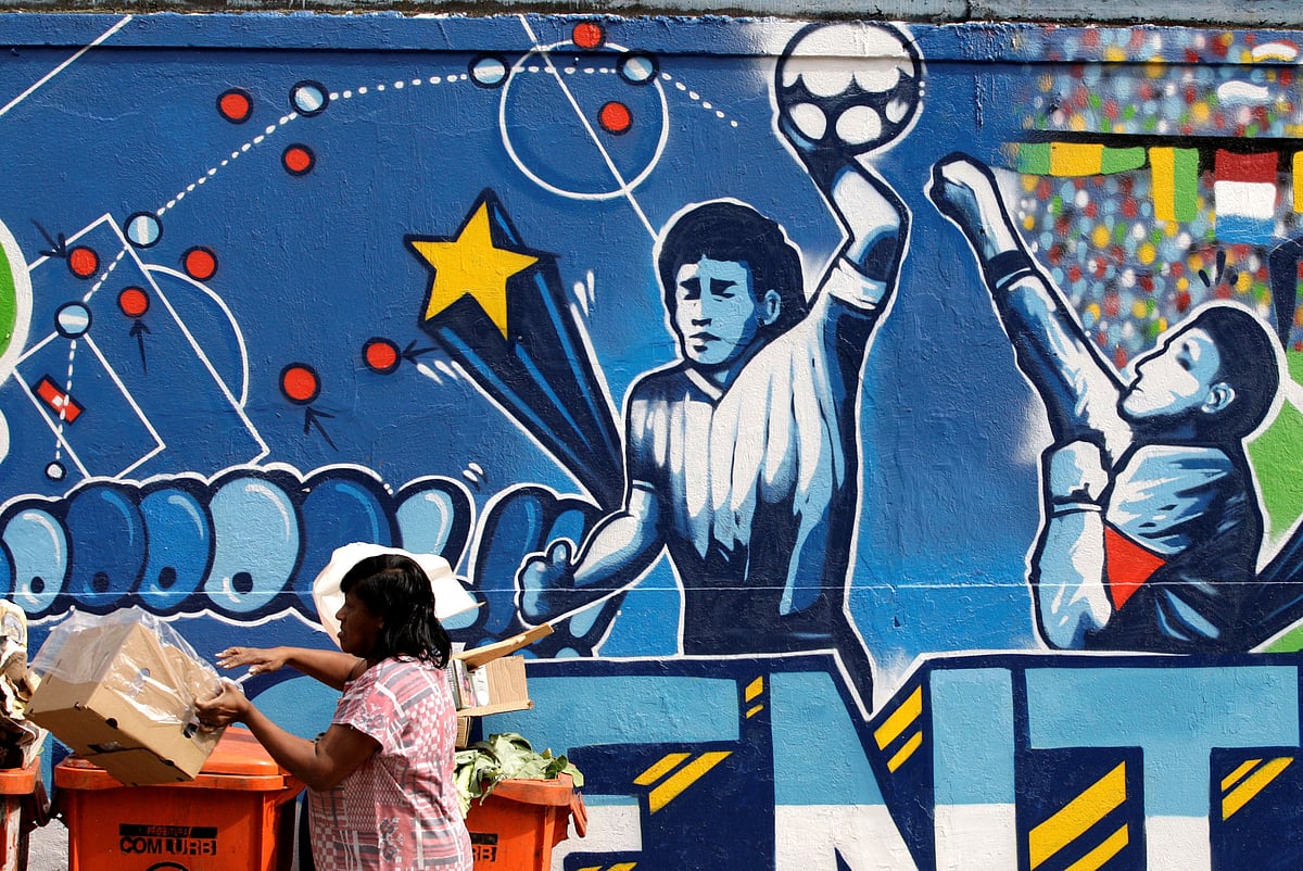A resident stands near a mural depicting the famous "Hand of God" goal by former Argentine soccer star Diego Maradona in Rio de Janeiro on 21 May  2010.