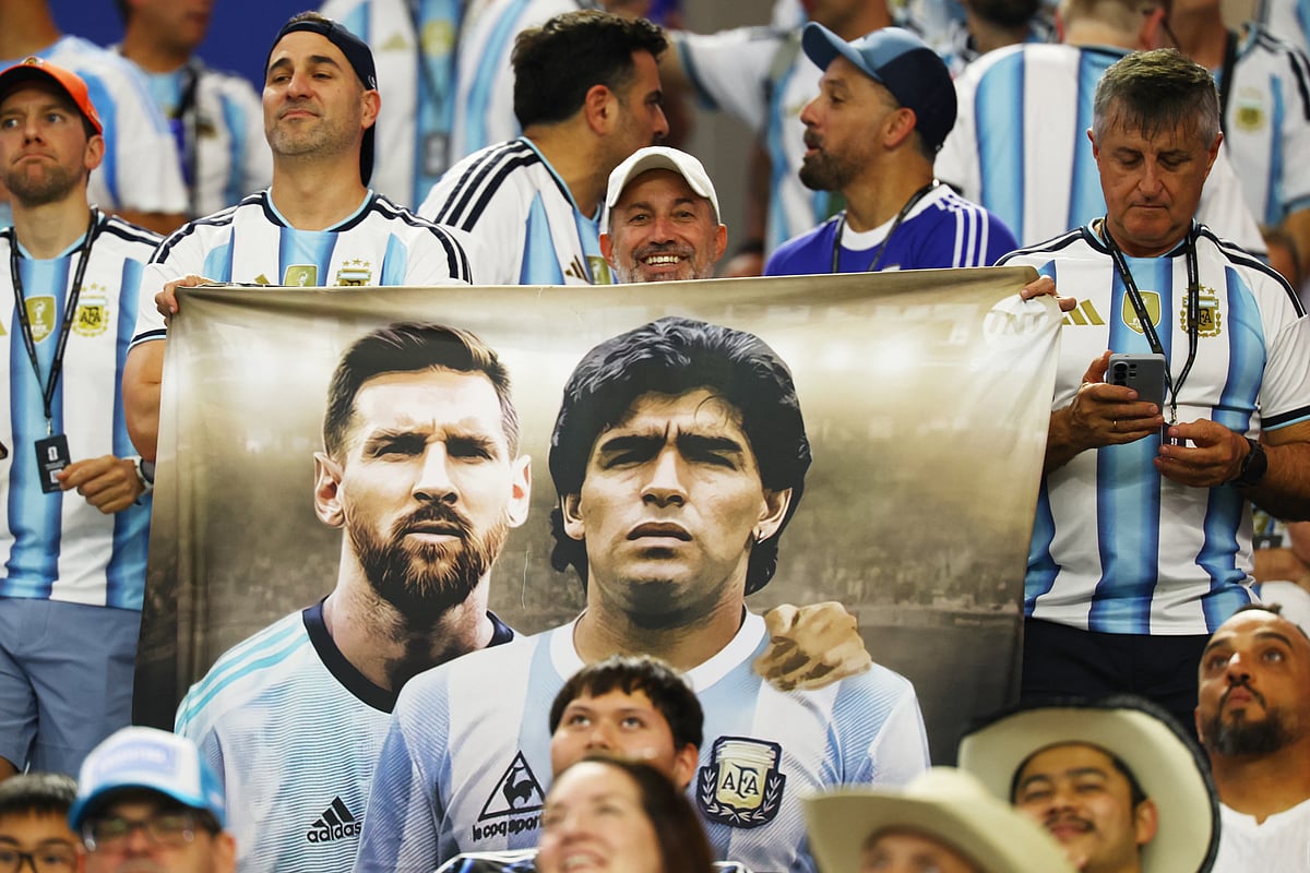 An Argentina fan with a banner featuring Argentina's Lionel Messi and Diego Maradona inside the stadium before the match.