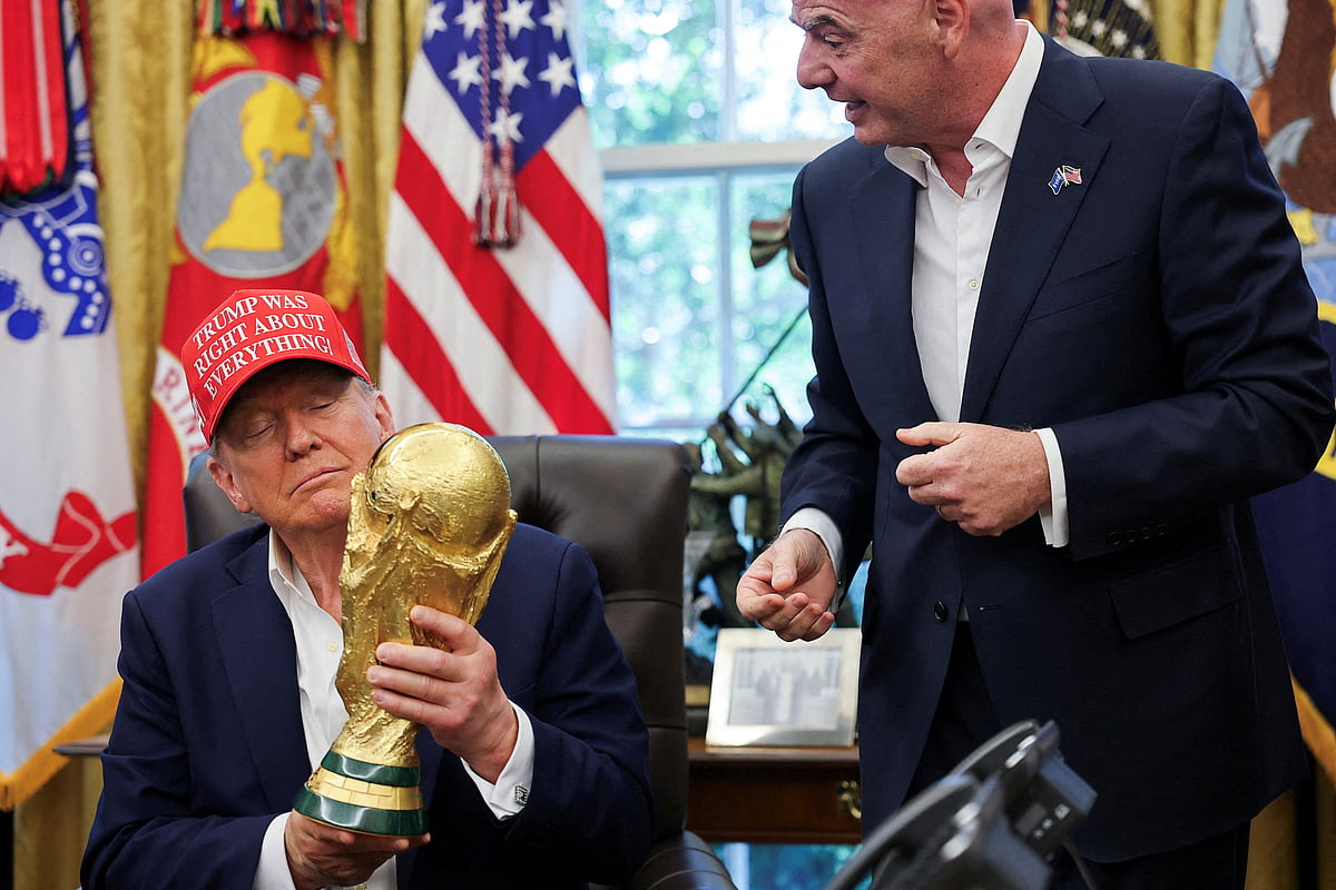 US President Donald Trump holds the FIFA World Cup Trophy, as he makes an announcement on the 2026 FIFA World Cup, as FIFA president Gianni Infantino stands next to him, in the Oval Office at the White House in Washington, DC, US, August 22, 2025.